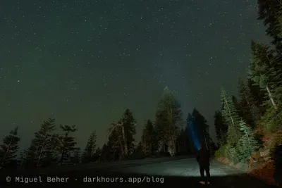 A stargazer shining a flashlight beam into the night sky on Mt Ashland, Oregon